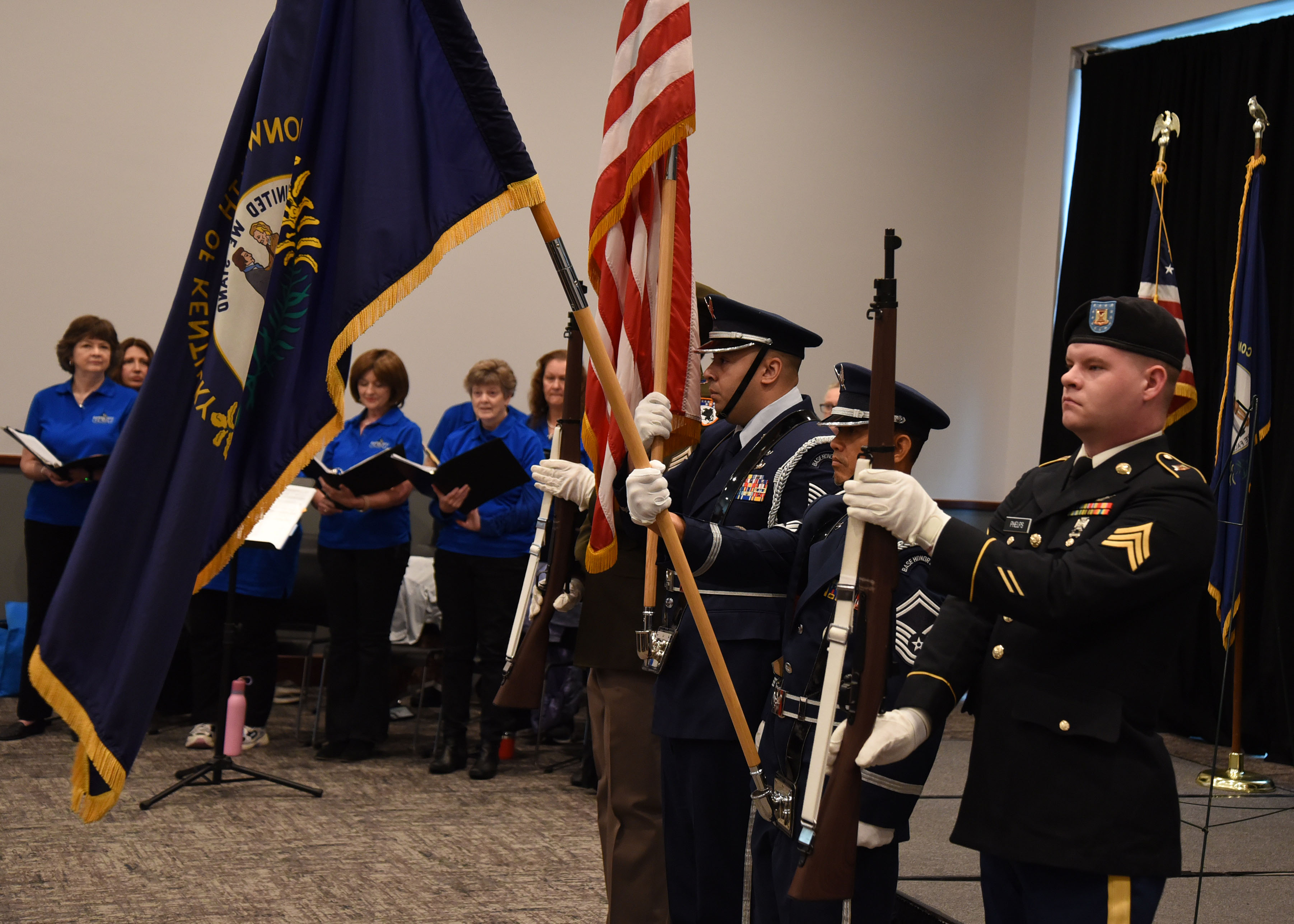 Four men perform a color guard service in front of a crowd of people.