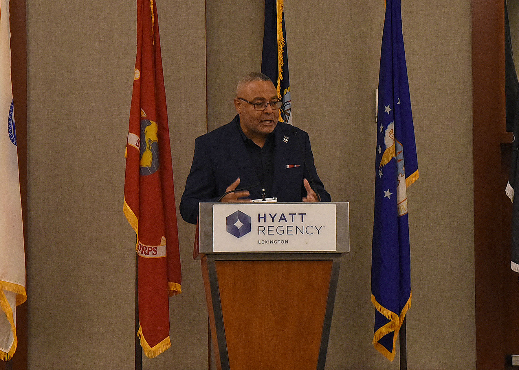 A man in a suit speaks at a podium.