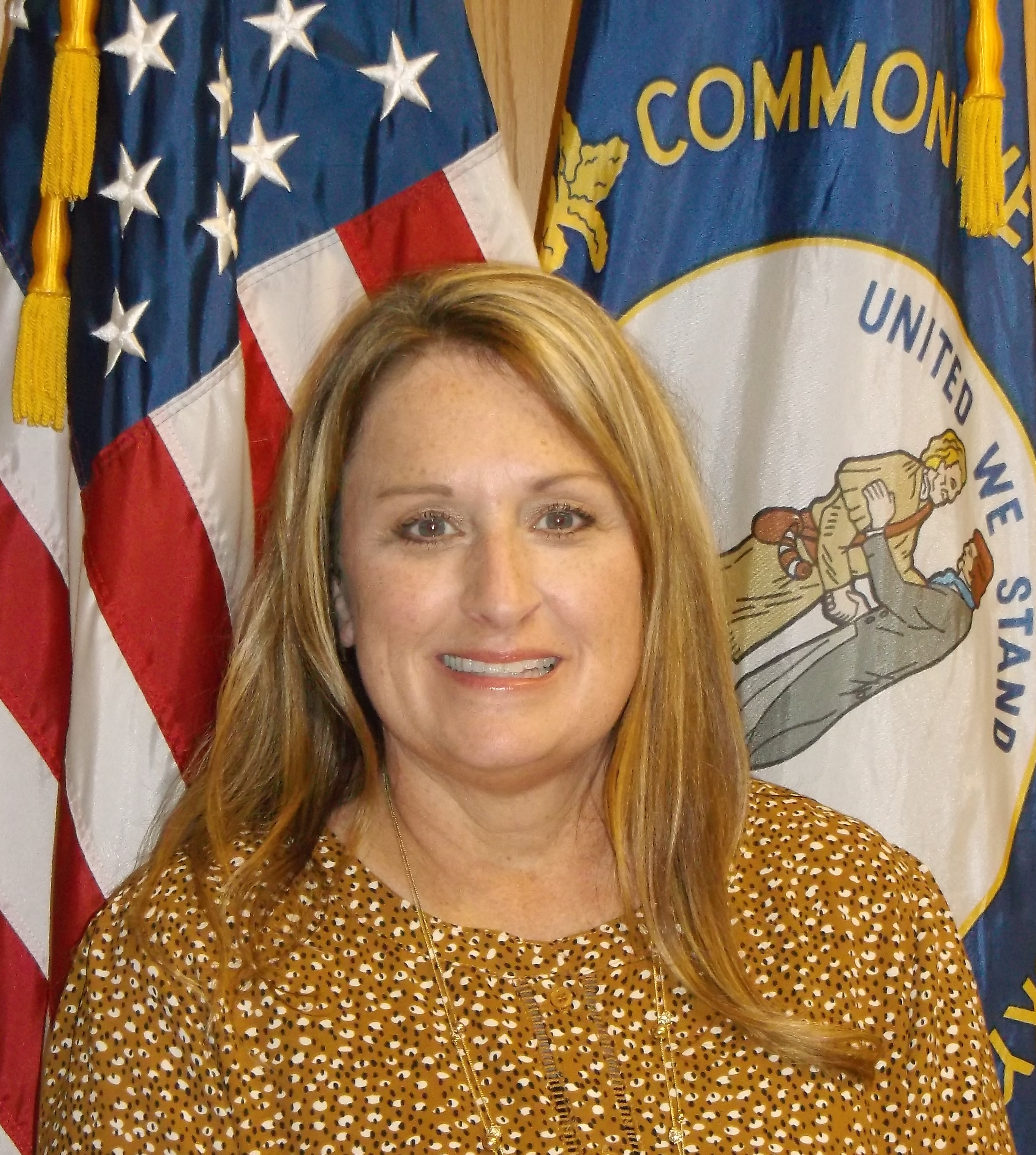 Portrait image of Administrator LaDonna Scott standing in front of  United States flag and Kentucky flag.